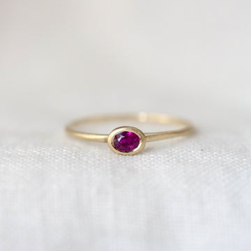 Gold ring with a red gemstone on a white background