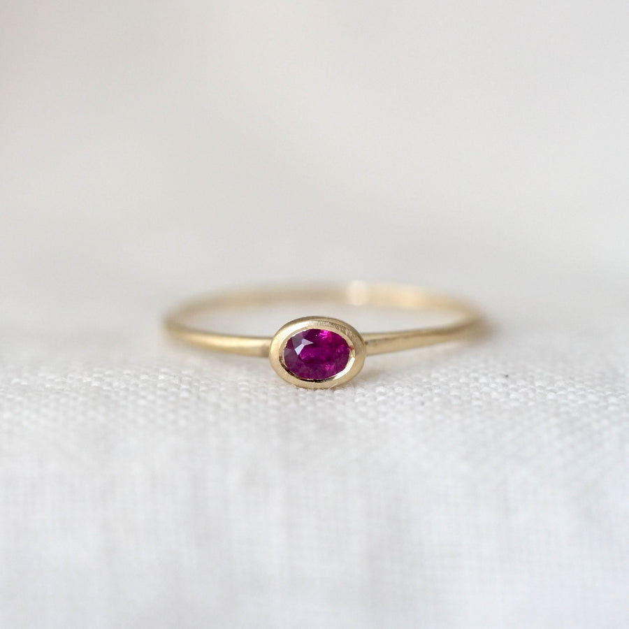 Gold ring with a red gemstone on a white background