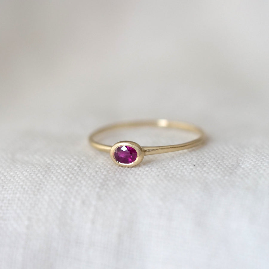 Gold ring with a Ruby gemstone on a white fabric background