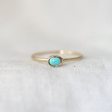 Gold ring with a turquoise gemstone on a white background