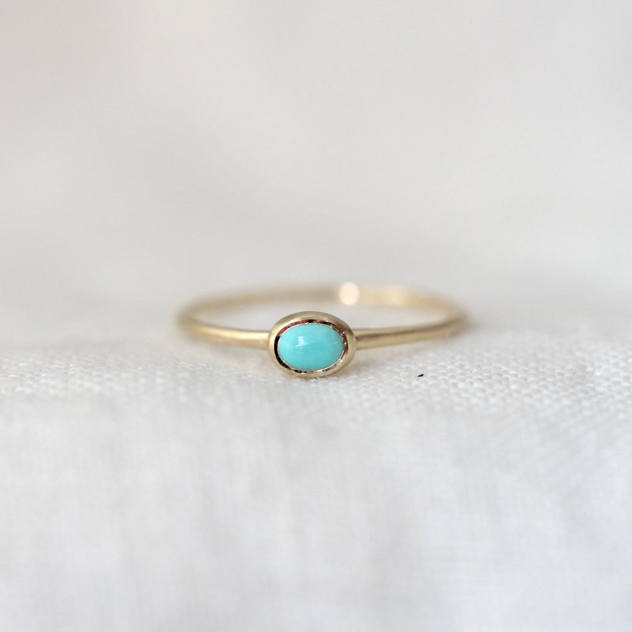Gold ring with a turquoise gemstone on a white background