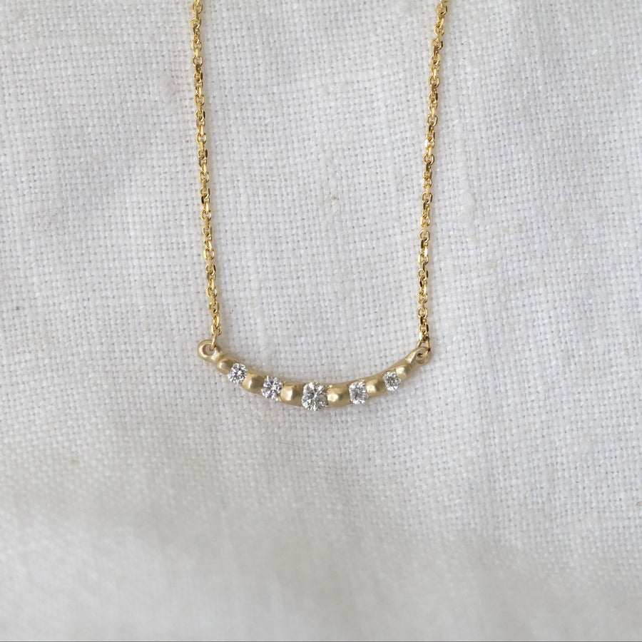 Gold necklace with small diamonds on a light fabric background