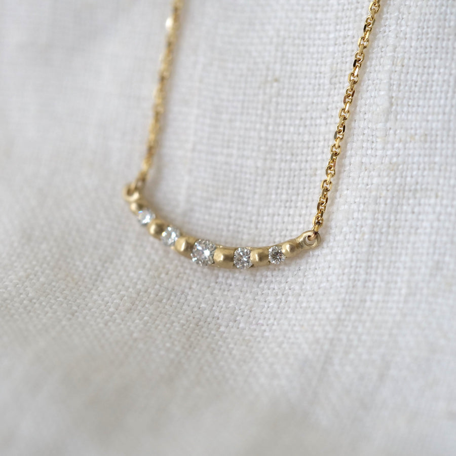 Gold necklace with small diamonds on a white fabric background