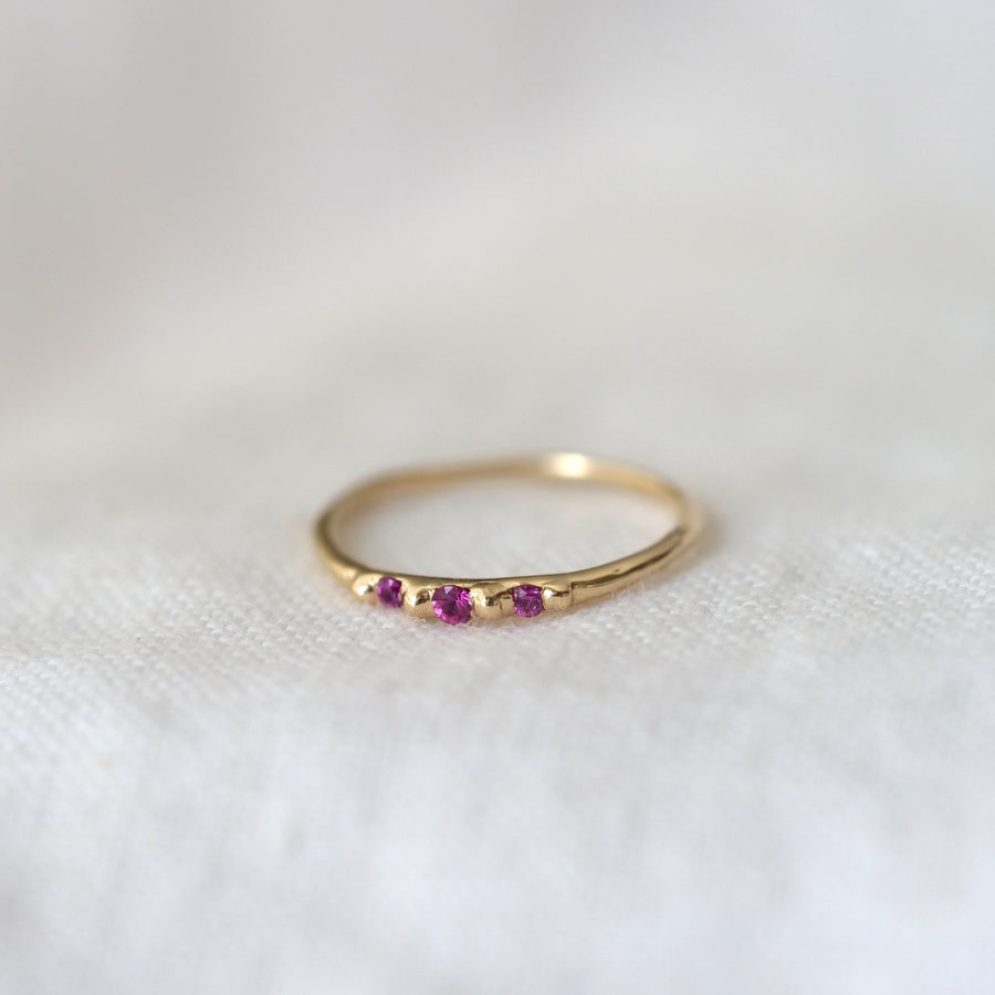 Gold ring with pink gemstones on a white fabric background
