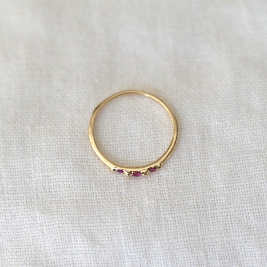 Gold ring with embedded gemstones on a light fabric background