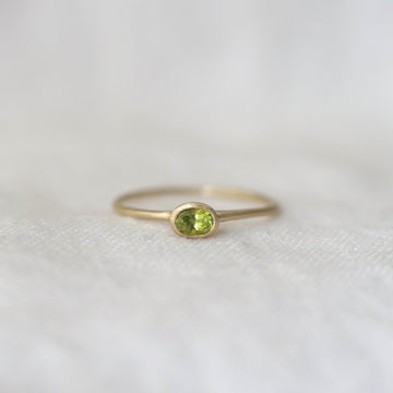 Gold ring with a green gemstone on a white fabric background