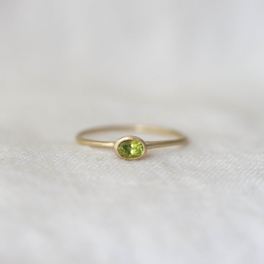 Gold ring with a green gemstone on a white fabric background