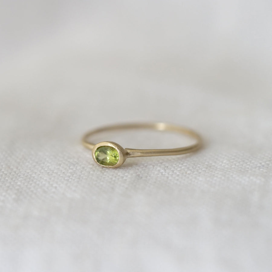 Gold ring with a green gemstone on a white fabric background