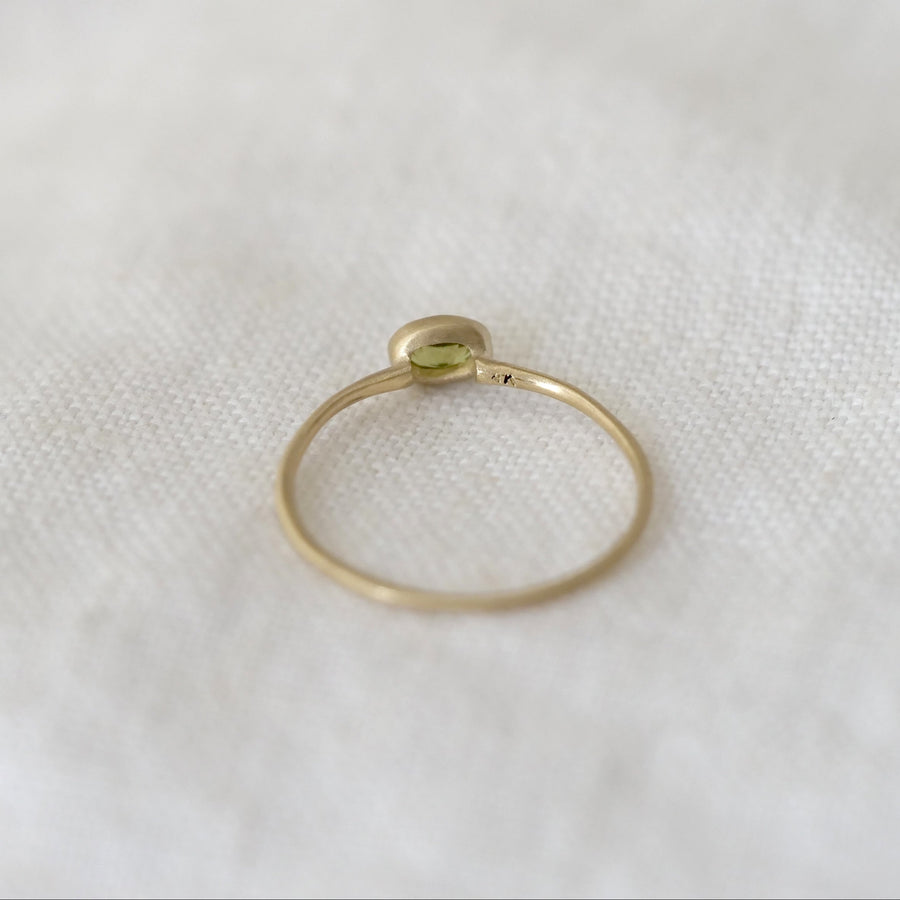 Gold ring with a small gemstone on a white fabric background