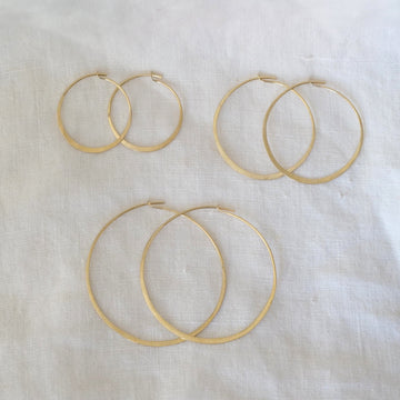 Set of gold hoop earrings on a white fabric background