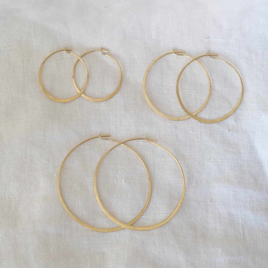 Set of gold hoop earrings on a white fabric background