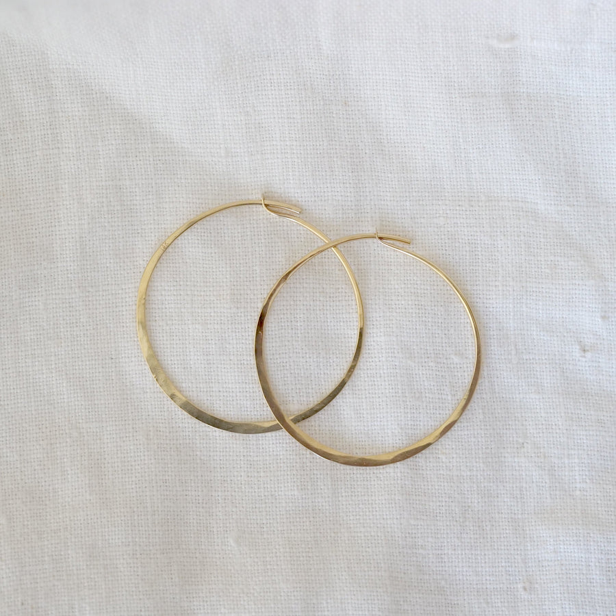 Gold hoop earrings on a light fabric background