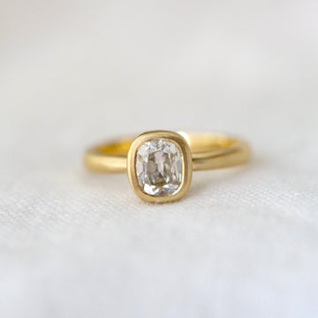 Gold ring with a long moval diamond on a white fabric background