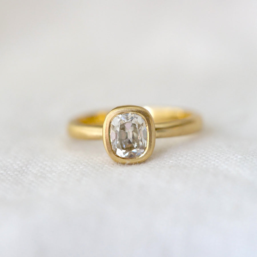 Gold ring with a long moval diamond on a white fabric background