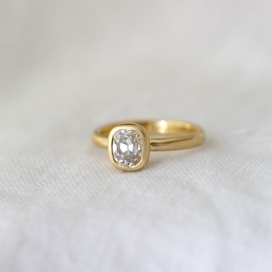 Gold ring with a diamond on a white fabric background