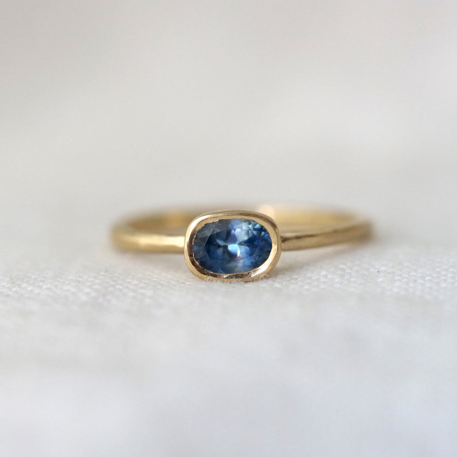 Gold ring with an oval blue gemstone on a white background