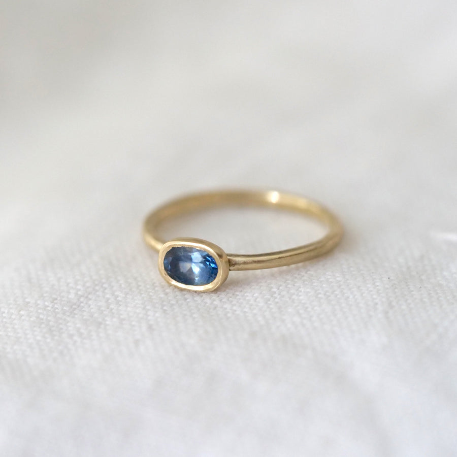 Gold ring with a blue gemstone on a white fabric background