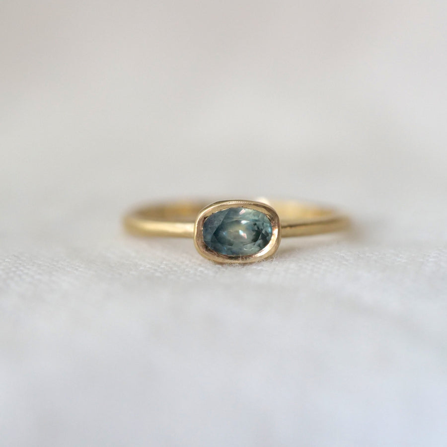 Gold ring with a blue gemstone on a white background