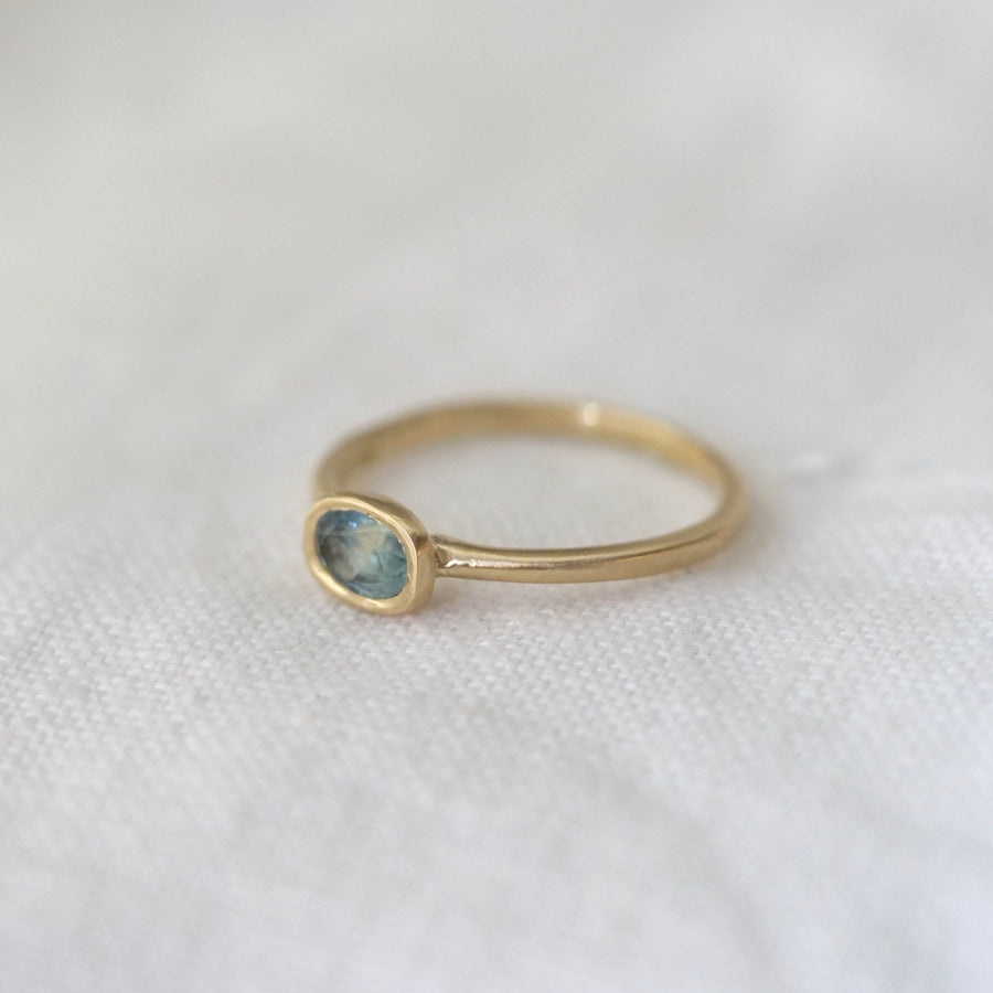 Gold ring with a green gemstone on a white fabric background