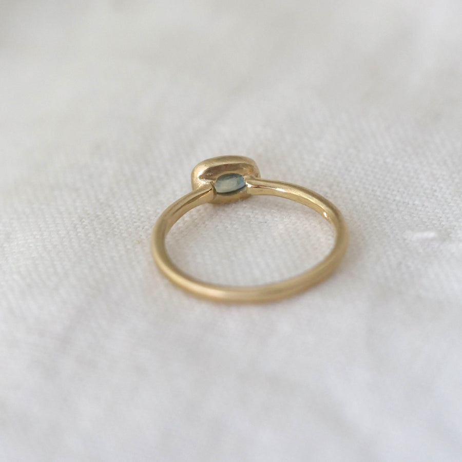 Gold ring with a gemstone on a white textured surface