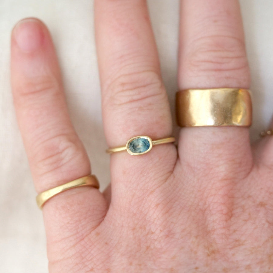Hand wearing three gold rings with a white background