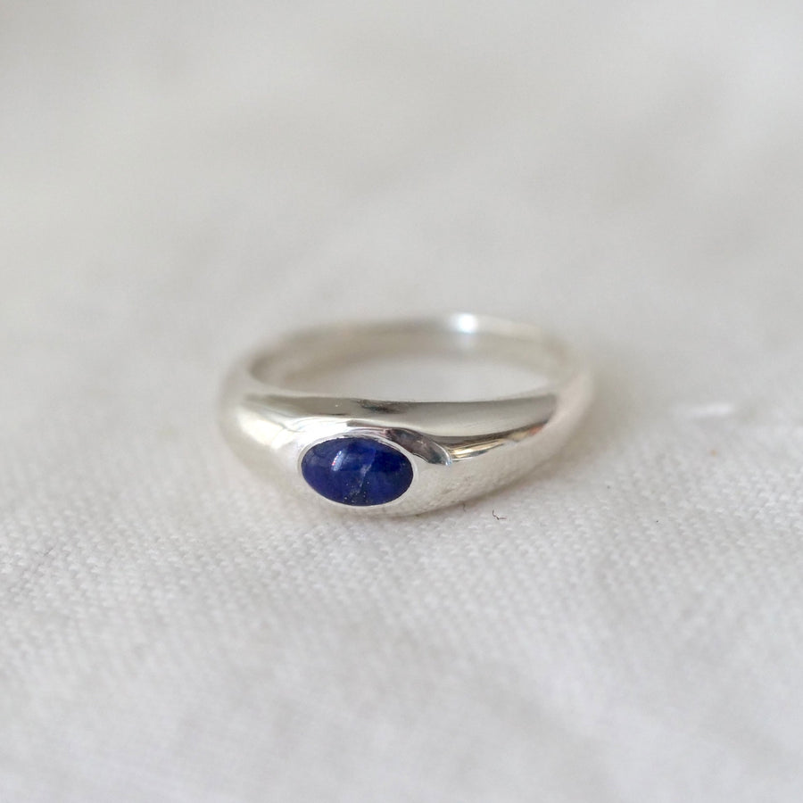 Silver ring with a blue stone on a white fabric background