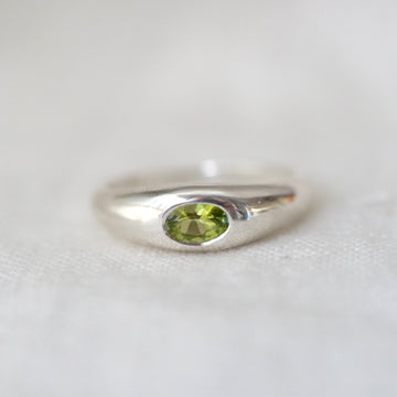 Silver ring with a green gemstone on a white background