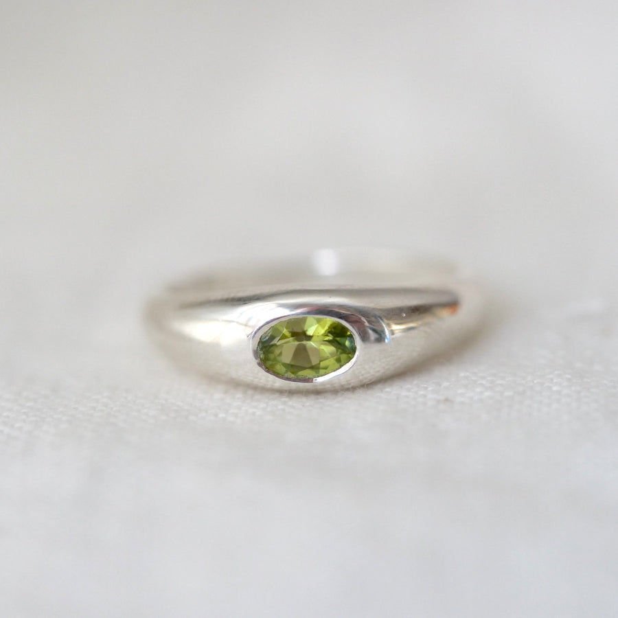 Silver ring with a green gemstone on a white background