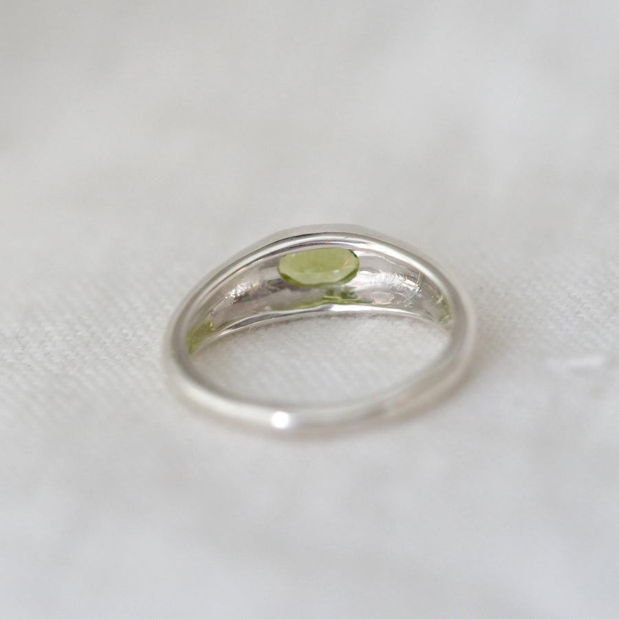 Silver ring with a green stone on a white background