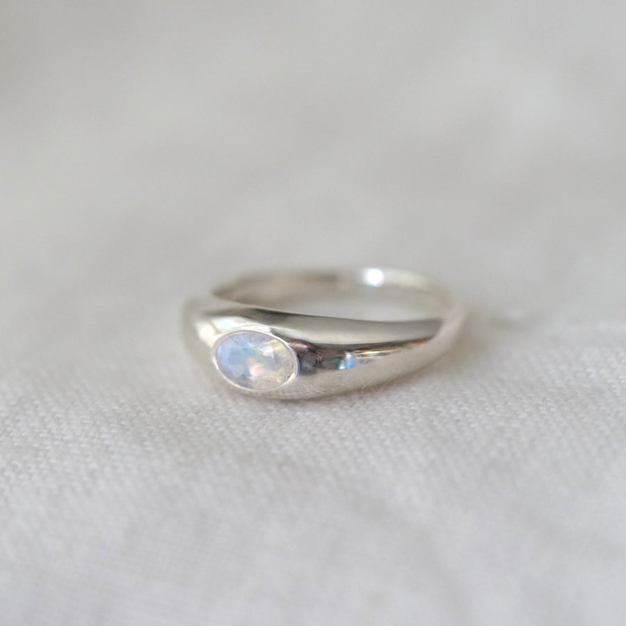 Silver ring with a moonstone on a light fabric background