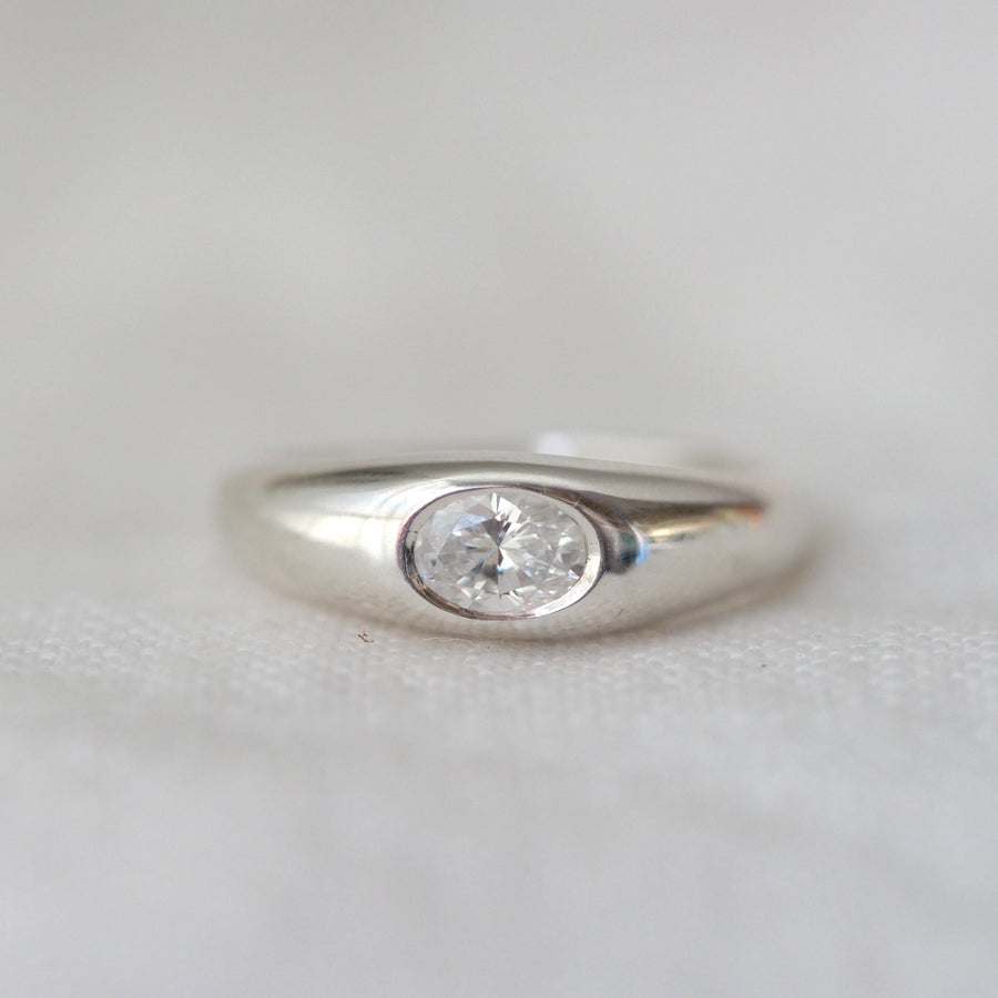 Silver ring with a diamond on a light gray background
