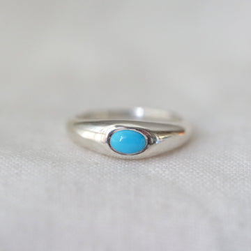 Silver ring with a turquoise stone on a light gray background