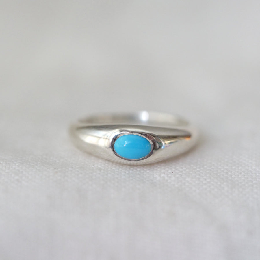 Silver ring with a turquoise stone on a light gray background