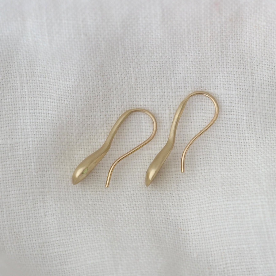 Pair of gold earrings on a light fabric background
