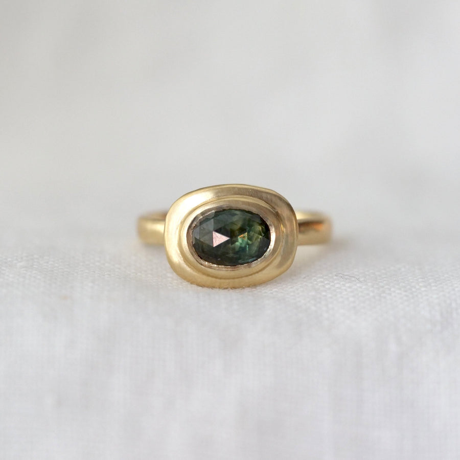 Gold ring with a green gemstone on a white background