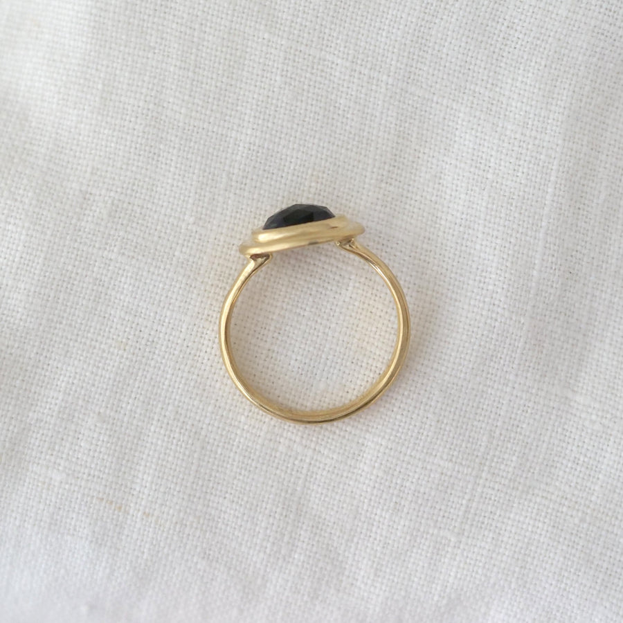Gold ring with a black stone on a white fabric background