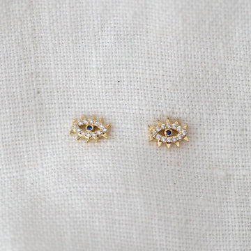 Pair of gold earrings with gemstones on a light fabric background