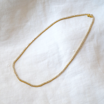 4 Prong Tennis Necklace with 5ct of white Diamonds, 16 inches long, on white linen backdrop 