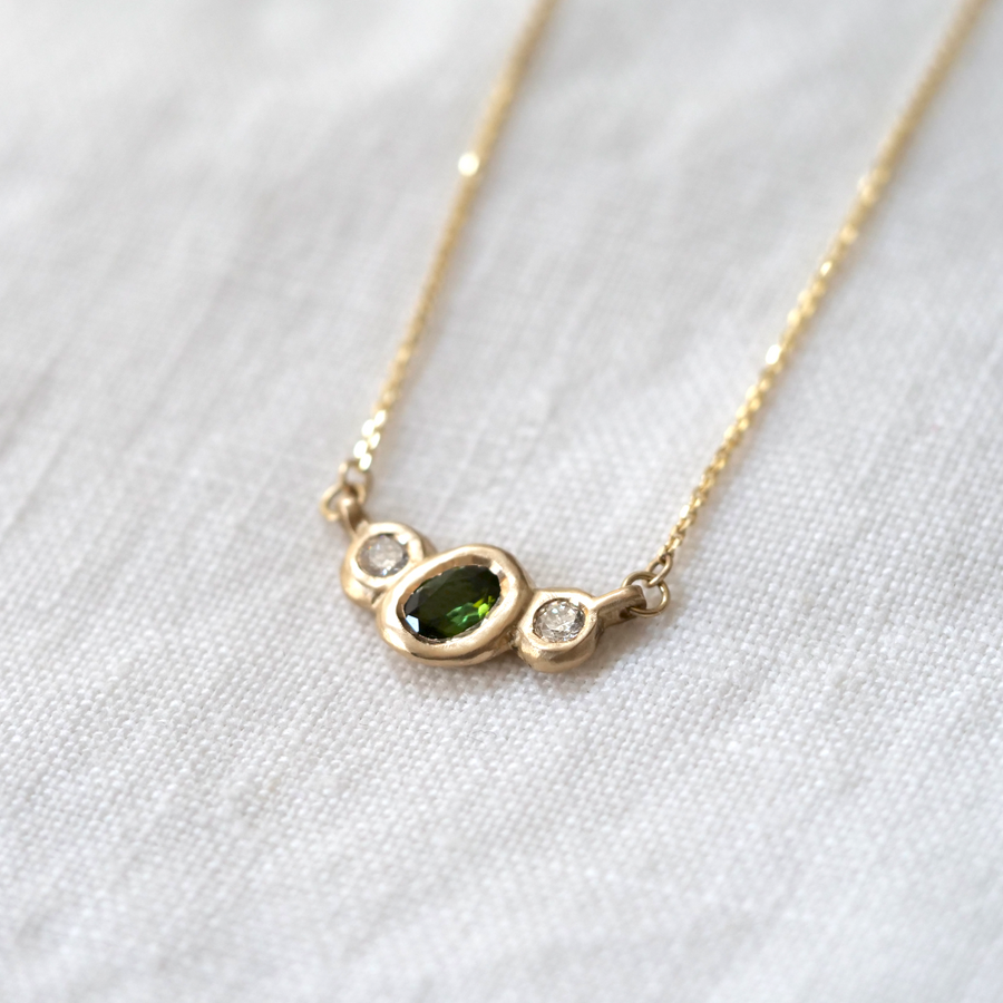 Organically sculpted 3 stone necklace, with one larger oval cut green Tourmaline and 2 small round diamonds on either side, bezel set in 14k yellow gold.  Marisa Mason Jewelry