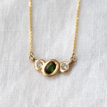 Organically sculpted 3 stone necklace, with one larger oval cut green Tourmaline and 2 small round diamonds on either side, bezel set in 14k yellow gold.  Marisa Mason Jewelry