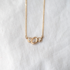 2 of 3: Organically sculpted 3 stone necklace, with one larger oval cut diamond and 2 small round diamonds on either side, bezel set in 14k yellow gold.  