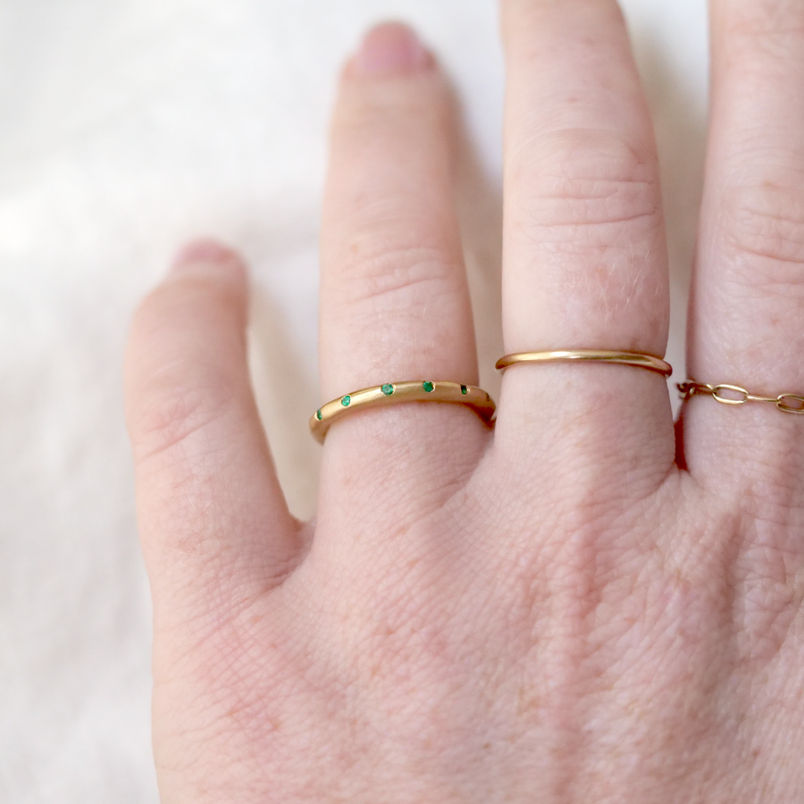 Softly matte 18k gold rustic band with a scattering of Emeralds.