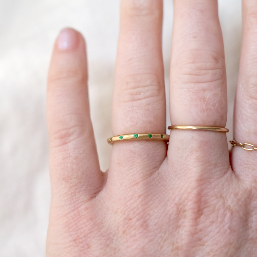 Softly matte 18k gold rustic band with a scattering of Emeralds.