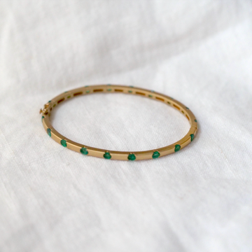 Stunning emerald and 14k yellow gold bangle, with 18 emeralds evenly spaced around it. Hinge clasp, oval shape for comfortability.