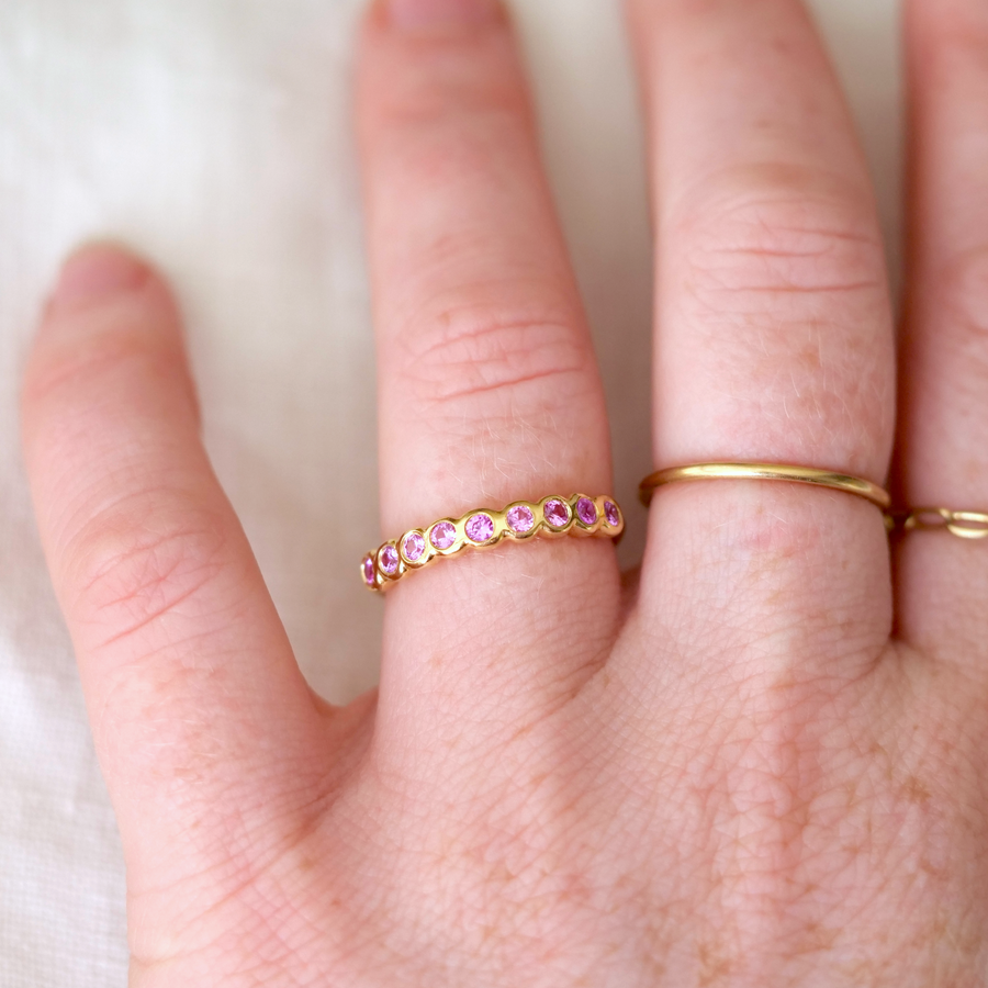 Pink Sapphires set in 18k yellow gold -- the stones has a pink hue with so much personality. Perfect for stacking or an unconventional wedding band. on models hand