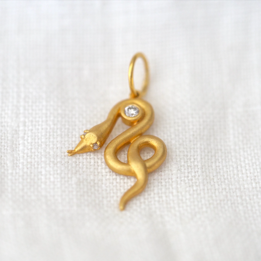 18kt gold pendant of a snake coiled around a 2mm white Diamond, with two small diamonds in the eyes.