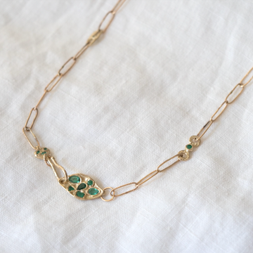 This paperclip chain features a variety of emeralds delicately placed on a hand-crafted textured clasp, complemented by textured cast links with emeralds.