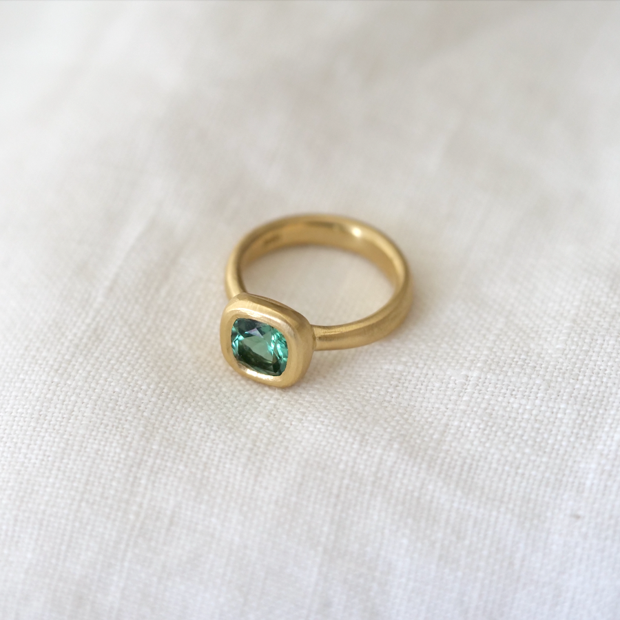 A magically verdant cushion-cut teal tourmaline, set in 18K gold and set high enough to sit perfectly next to a band.
