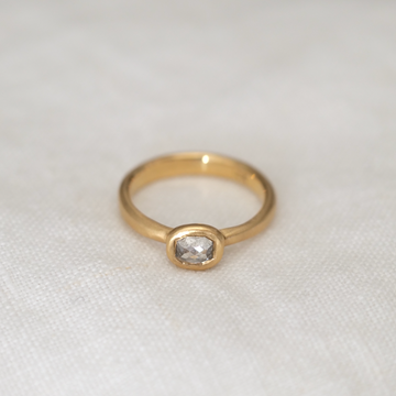 Simplicity and elegance is what you will find in this oval rose cut cushion shaped grey diamond, set in 18k yellow gold bezel set ring.
