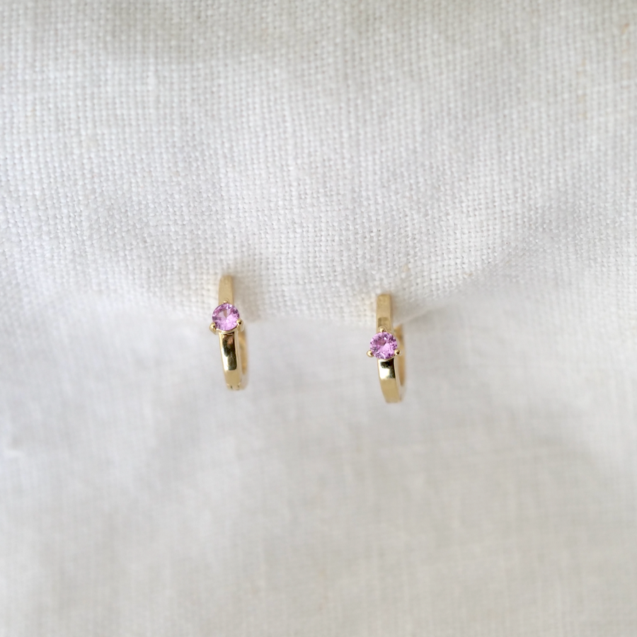 Pink sapphires are securely prong set in the center of these wide gold hoops, making them sit closer to the lobe